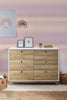 Wooden dresser with decorative items against a pink wallpaper