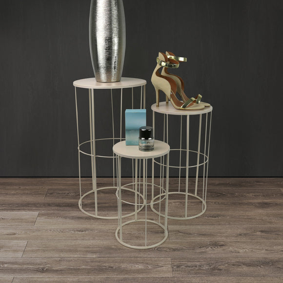 Set of three round side tables with metal frame and wooden top in a dark room.