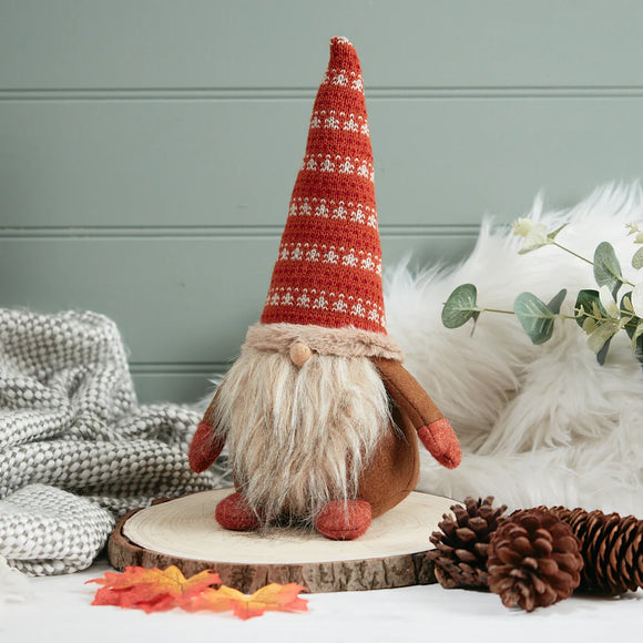 Decorative gnome with a red patterned hat on a wooden base with pinecones and foliage.