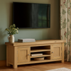 Wooden TV stand with a television mounted on a wall in a room with  curtains.