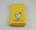 Yellow kitchen towel with Henrietta Hen design.
