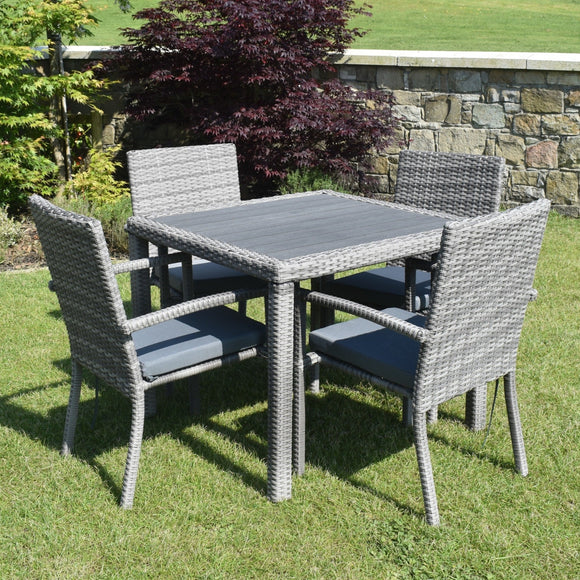 Outdoor patio set with a table and four chairs on a grassy area.