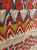 Close-up of a patterned rug with red, yellow, and blue colors.