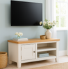White TV stand with wooden top in a room with light blue walls and a window.