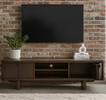 Wooden TV stand with a television, plant, and decorative items against a brick wall.