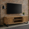 Wooden TV stand with a television mounted on a brick wall in a room with a window and plant.