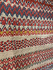 Close-up of a patterned fabric with zigzag and chevron designs in red, blue, and beige.