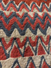 Close-up of a patterned rug with red, blue, and beige colors.